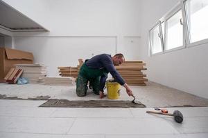 trabajador instalando las baldosas cerámicas con efecto madera en el suelo foto