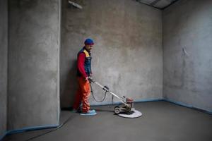 worker performing and polishing sand and cement screed floor photo