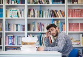 portrait of student while reading book  in school library photo