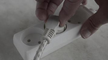 the man pulls the plug out of the socket of an electric extension cord.saving electricity in the house. video