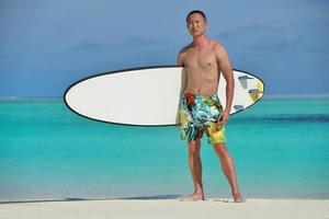 hombre con tabla de surf en la playa foto