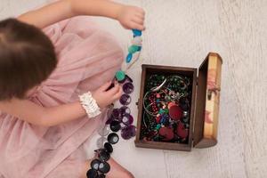 niña disfrutando mientras juega con las joyas de la madre foto