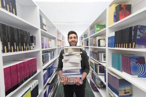 Student holding lot of books in school library photo