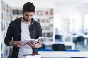 portrait of student while reading book  in school library photo