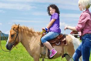 niño montar pony foto