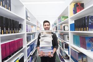 Student holding lot of books in school library photo