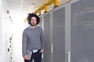 IT engineer working on a tablet computer in server room photo