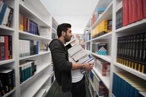 Student holding lot of books in school library photo