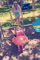 mother and daughter swinging in the park photo