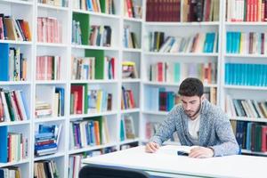 portrait of student while reading book  in school library photo