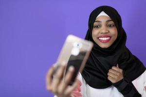 african muslim woman with a beautiful smile takes a selfie with a cell phone photo