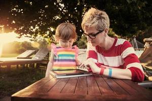 mom and her little daughter using tablet computer photo