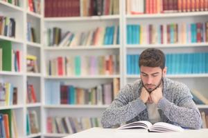portrait of student while reading book  in school library photo