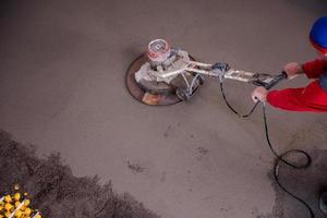 worker performing and polishing sand and cement screed floor photo