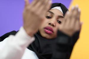 African Muslim woman makes traditional prayer to God, keeps hands in praying gesture, wears traditional white clothes photo