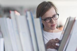 retrato de estudiante famale seleccionando un libro para leer en la biblioteca foto