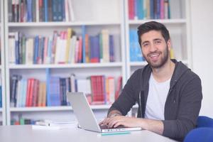 student in school library using laptop for research photo