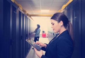 Female engineer working on a tablet computer in server room photo