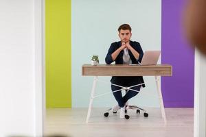 Smiling young man freelancer using laptop studying online working from home photo