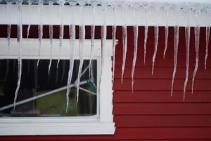 icicles on the roof of a red house in Norway photo