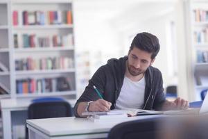 estudiante en la biblioteca escolar usando una computadora portátil para investigar foto