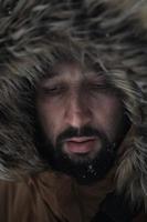 man at winter in stormy weather wearing warm  fur jacket photo