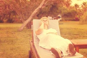 woman using mobile phone while lying on the sunbed photo