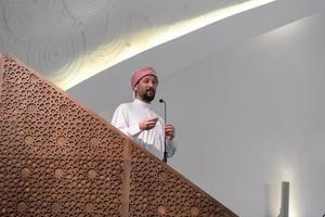 el joven imán árabe musulmán tiene un discurso en la oración del viernes por la tarde en la mezquita. foto