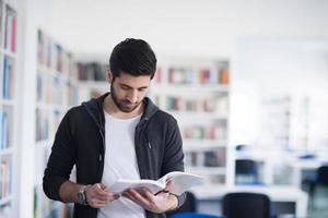 portrait of student while reading book  in school library photo
