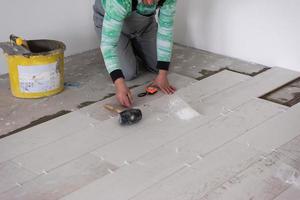 worker installing the ceramic wood effect tiles on the floor photo