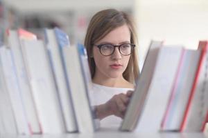 portrait of famale student selecting book to read in library photo