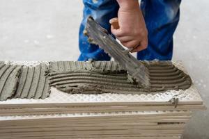 worker installing the ceramic wood effect tiles on the floor photo