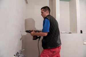 trabajador de la construcción perforando agujeros en el baño foto