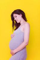 Portrait of pregnant woman over yellow background photo