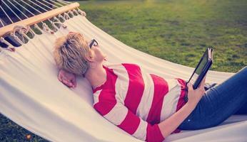 woman using a tablet computer while relaxing on hammock photo