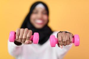 afro muslim woman promotes a healthy life, holding dumbbells in her hands photo