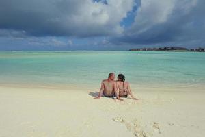 feliz pareja joven divertirse en la playa foto