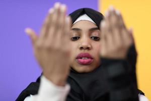 mujer musulmana africana hace oración tradicional a dios, mantiene las manos en gesto de oración, usa ropa blanca tradicional foto