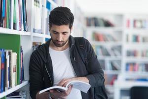 portrait of student while reading book  in school library photo