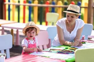 mamá y su pequeña hija dibujando imágenes coloridas foto