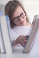 retrato de estudiante famale seleccionando un libro para leer en la biblioteca foto