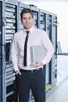 businessman with laptop in network server room photo