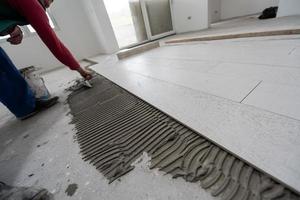 worker installing the ceramic wood effect tiles on the floor photo