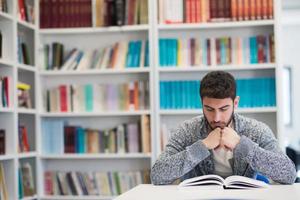 portrait of student while reading book  in school library photo