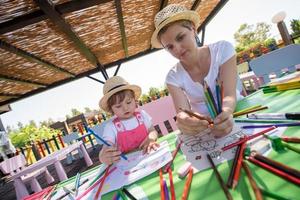 mamá y su pequeña hija dibujando imágenes coloridas foto