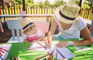 mamá y su pequeña hija dibujando imágenes coloridas foto