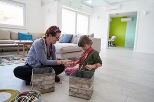 madre e hija pequeña jugando con joyas en casa foto