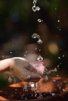 salpicando agua dulce en manos de mujer foto