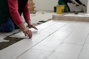 worker installing the ceramic wood effect tiles on the floor photo