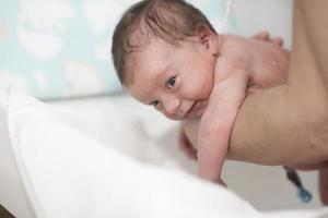 Newborn baby girl taking a first bath photo